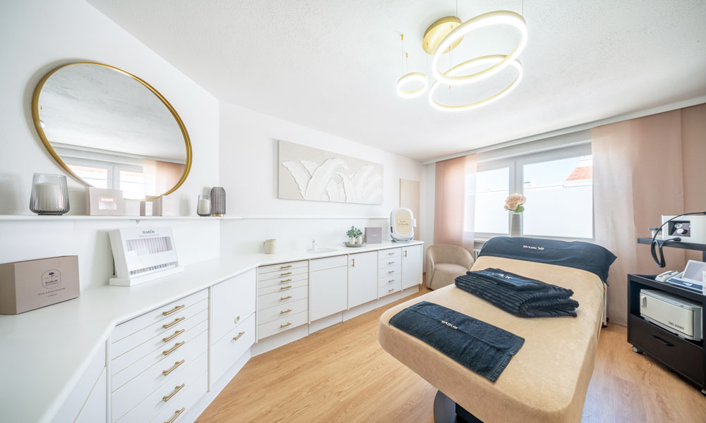 Behandlungsraum von BODY & Beauty mit Liege, Spiegel und Pflegeschrank